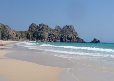 Low tide on uncovered sands, stretching from Porthcurno to the Logan Rock